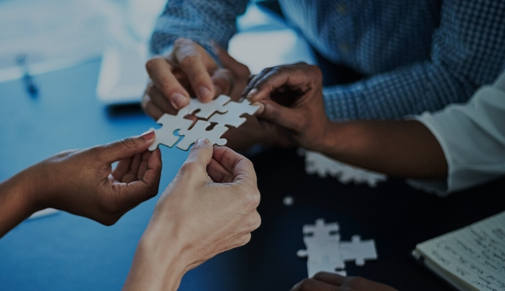 people holding puzzle pieces and putting them together